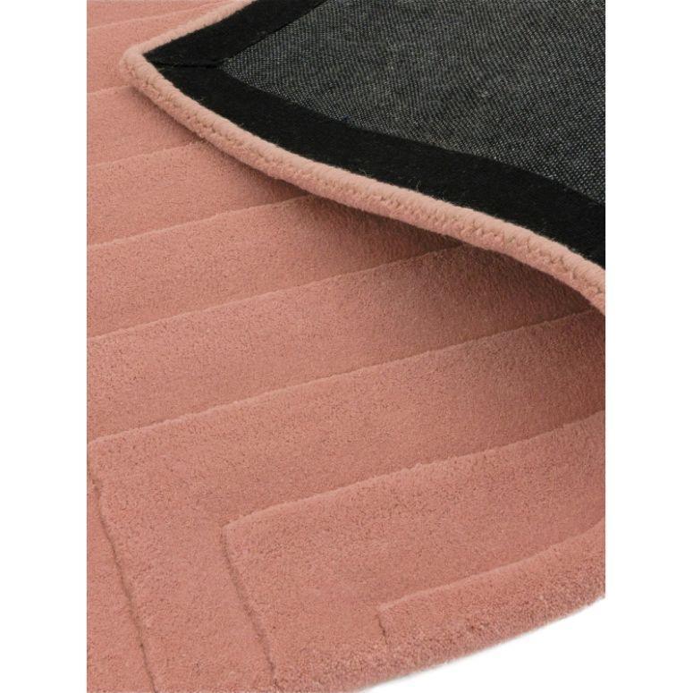 Blush pink textured rug with geometric pattern and black non-slip backing, closeup view