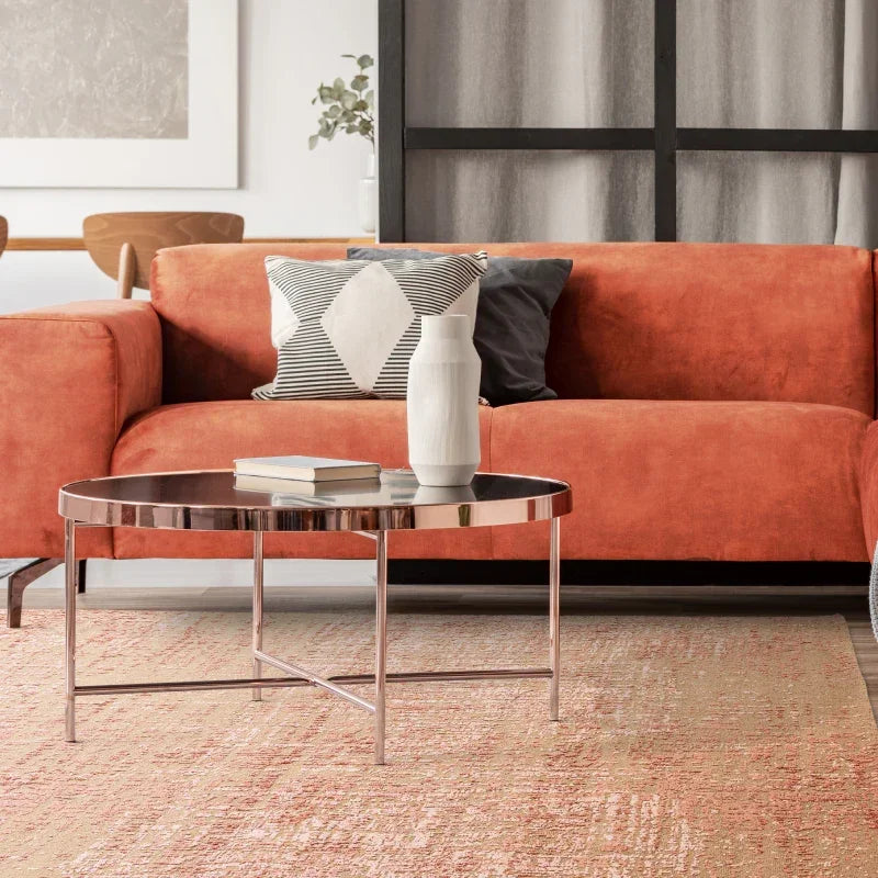 Orange velvet sofa with patterned cushions and round metal coffee table in modern living room