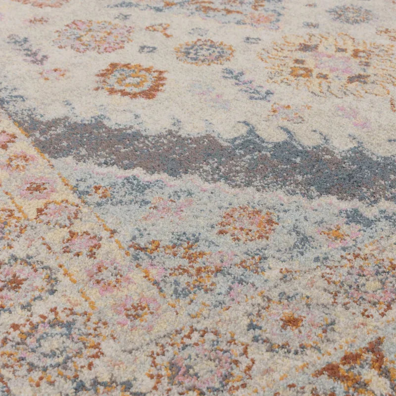 Closeup of patterned area rug with floral motifs in blue, gold, and pink tones