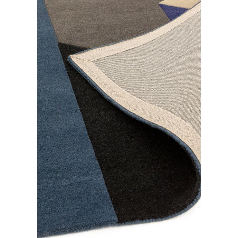 Geometric wool rug in blue, black, and beige with corner edge flipped to show backing
