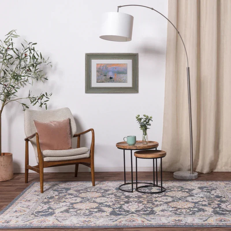 Modern armchair with cushion, nested wooden side tables and patterned rug in living room