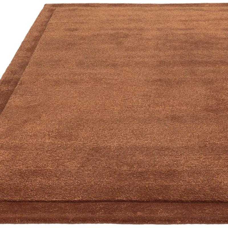 Rectangle brown area rug with subtle textured border, close-up corner view