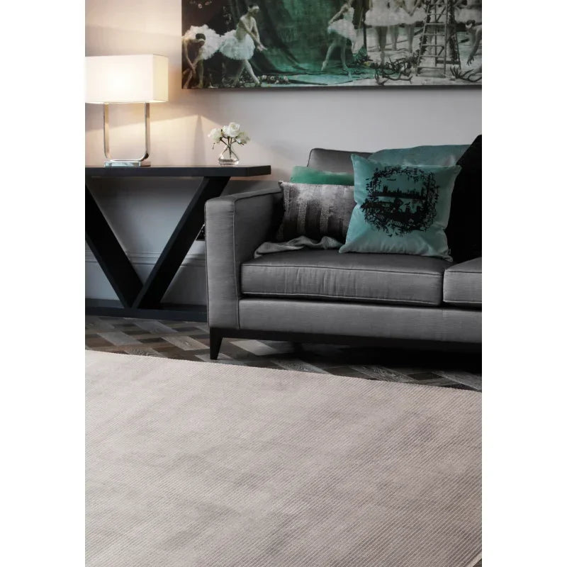 Modern grey sofa with teal accent cushions, neutral area rug, and contemporary console table