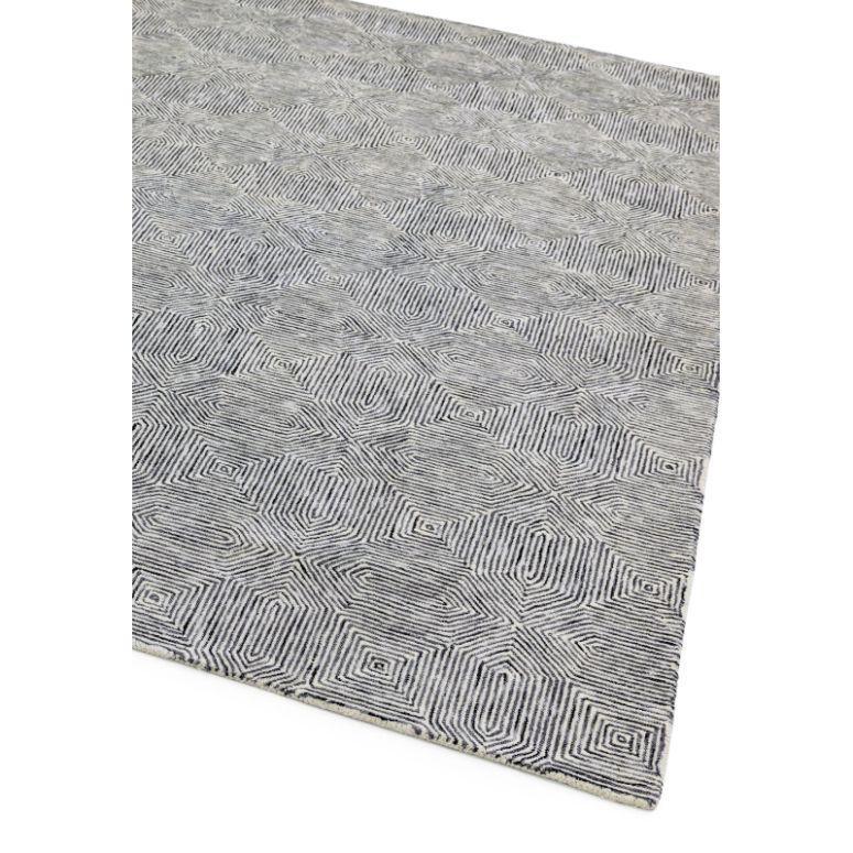 Grey geometric patterned rug with textured surface, angled corner view