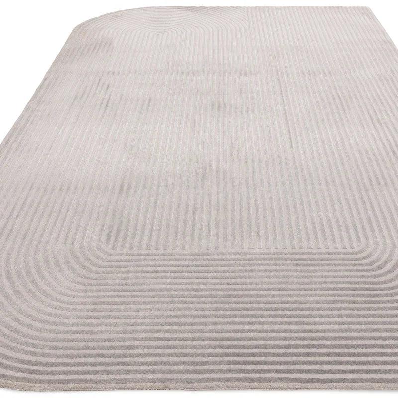 Light grey modern area rug with subtle geometric line pattern, rounded top left corner