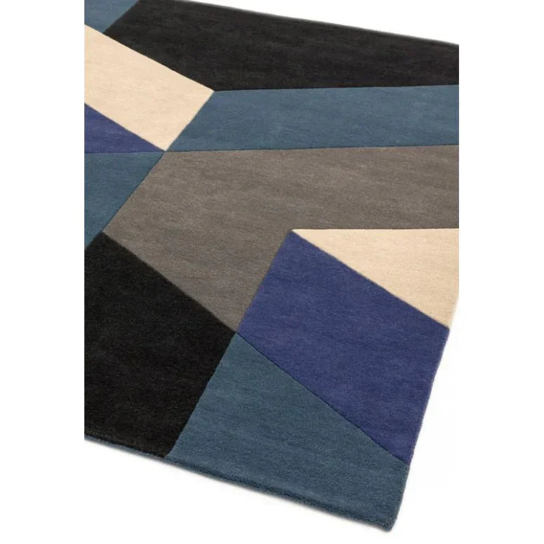 Geometric wool rug with blue, grey, black, and cream color blocks, corner angle view