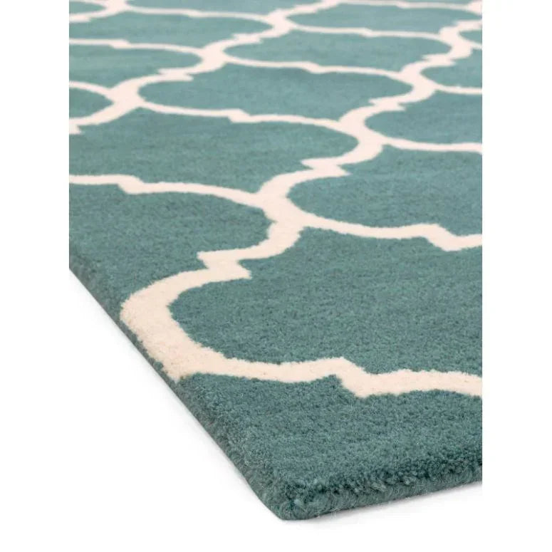 Teal area rug with white geometric pattern and plush texture, corner angle view