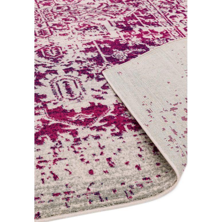 Pink and cream patterned rug with folded corner showing backing texture
