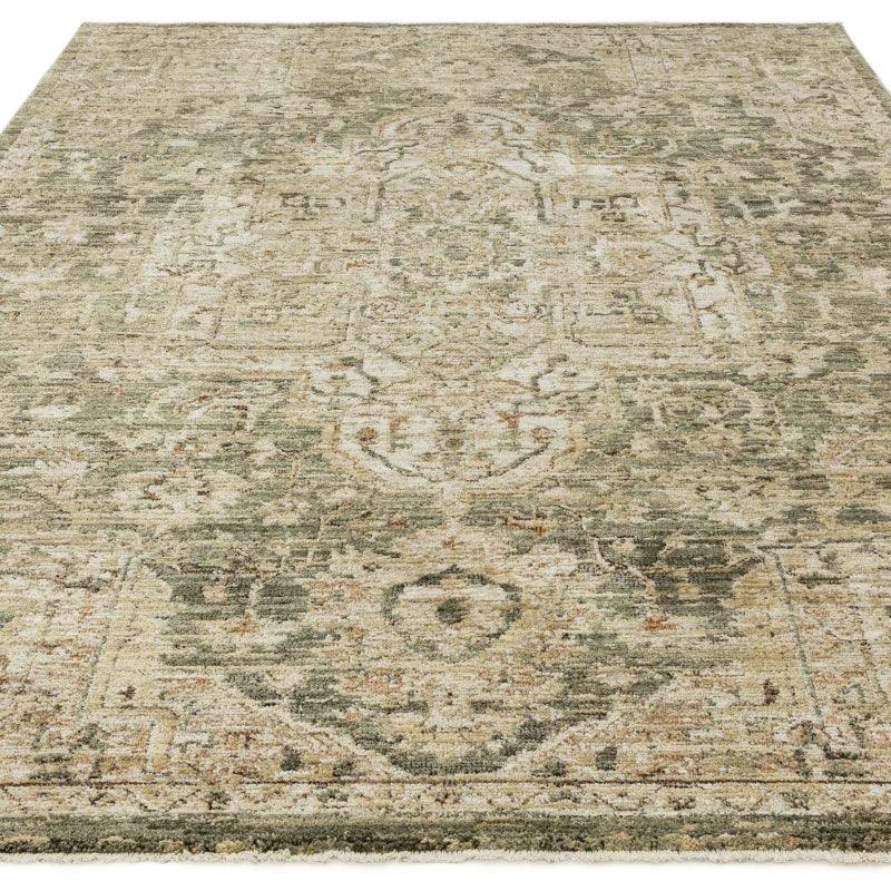 Large vintage style area rug with muted green and beige pattern on flat surface