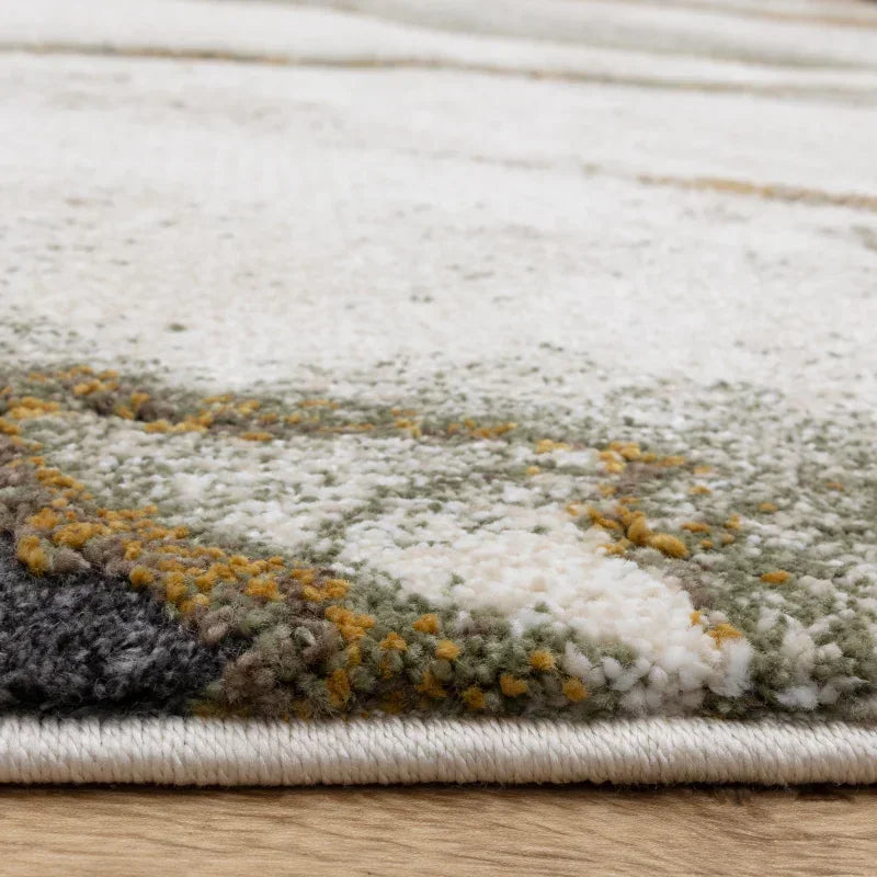 Close-up of area rug with beige, green, and yellow abstract pattern on wood floor