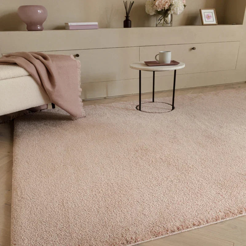 Blush pink shaggy rug in modern living room with cream sofa and round side table