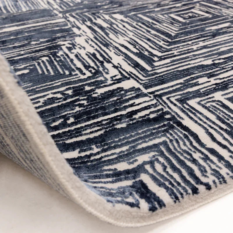 Blue and white geometric patterned rug corner close-up on light floor