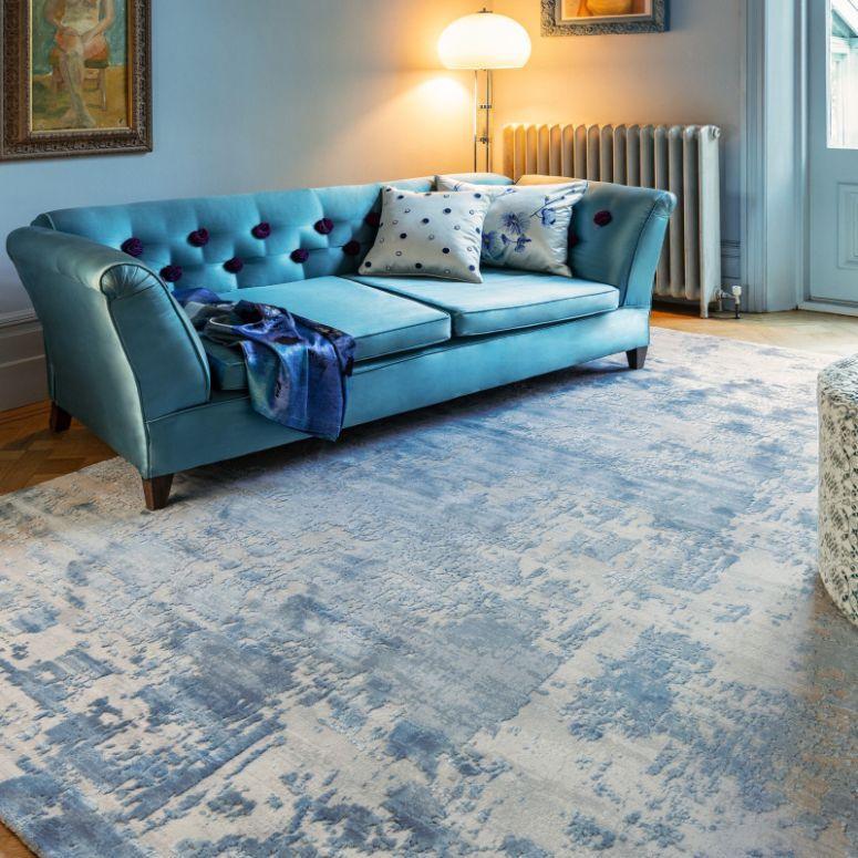 Blue velvet sofa with button detail and patterned cushions in a modern living room