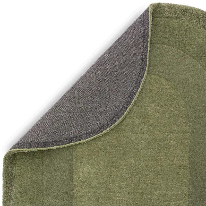 Green area rug corner folded to show non-slip backing and textured pile detail