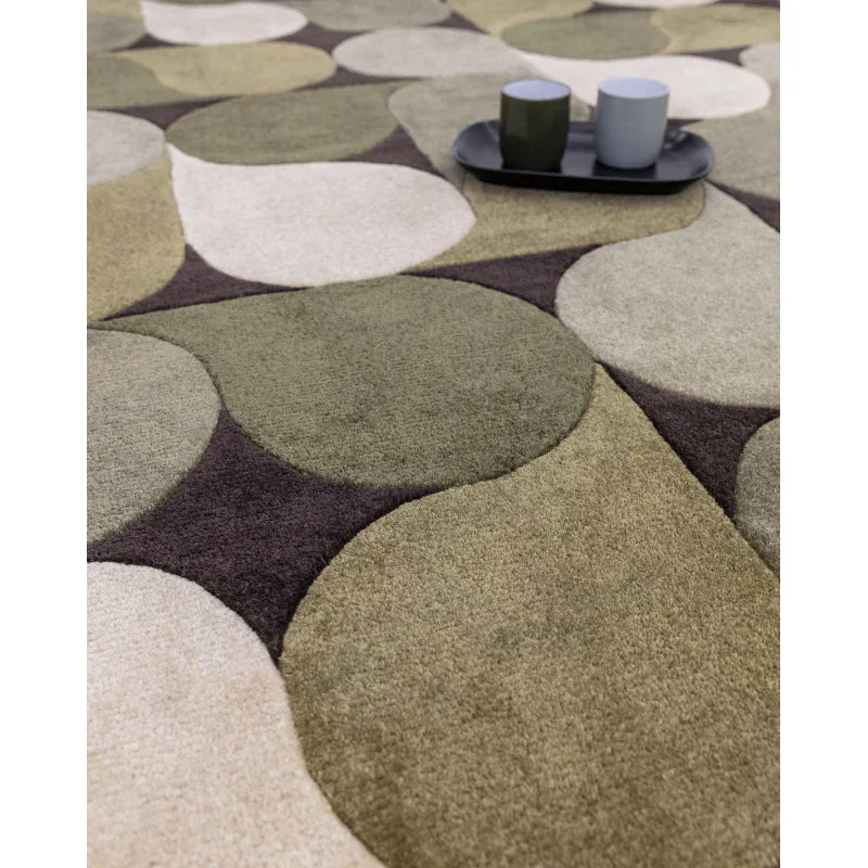 Geometric pattern rug in green, beige and brown with tray and two mugs on soft surface