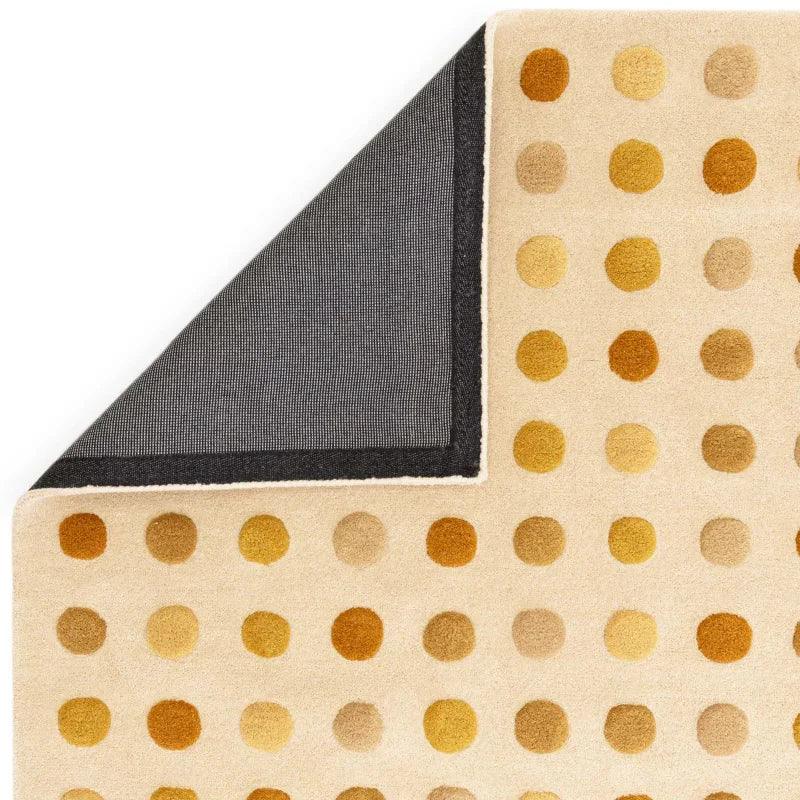 Beige wool rug with yellow and orange polka dots, corner flipped to show black backing
