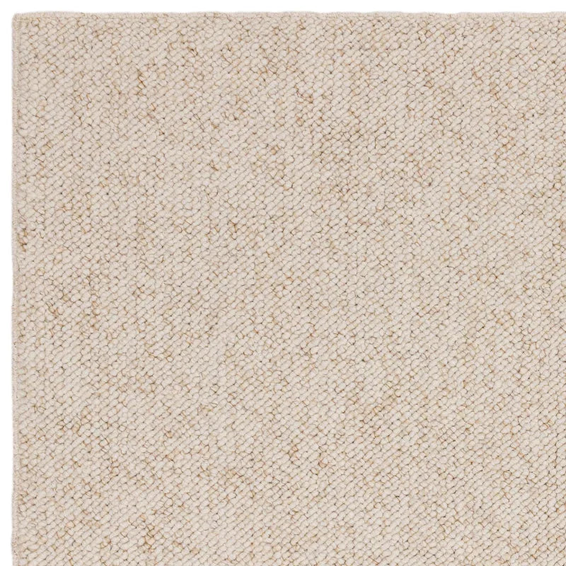 Beige woven rug corner showing textured wool material and natural finish