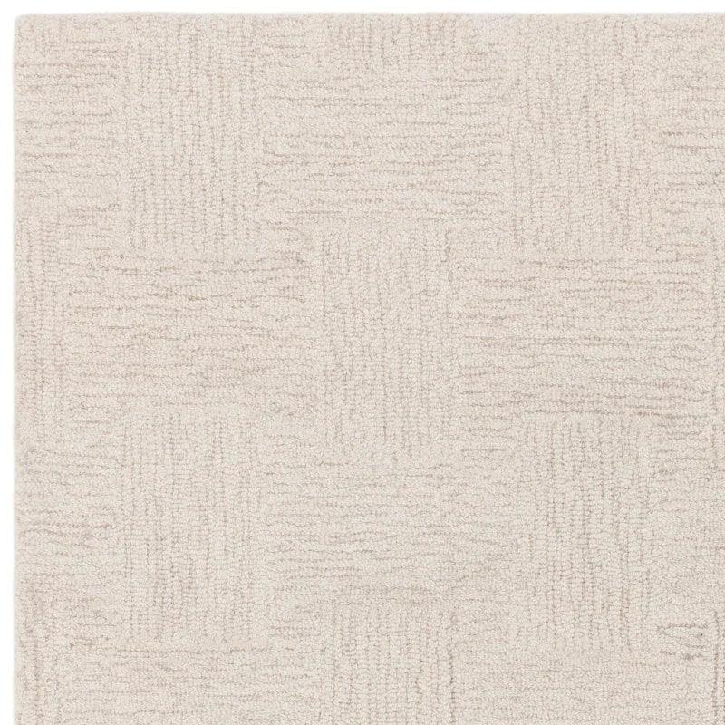 Beige textured rug with subtle geometric pattern, close view of woven carpet surface