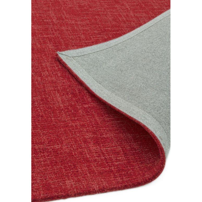 Red area rug with corner flipped to show grey backing
