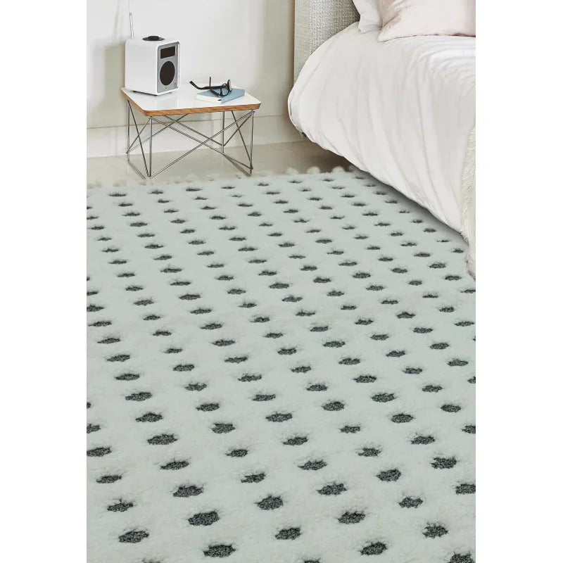 White and grey patterned area rug beside bed in modern bedroom setting