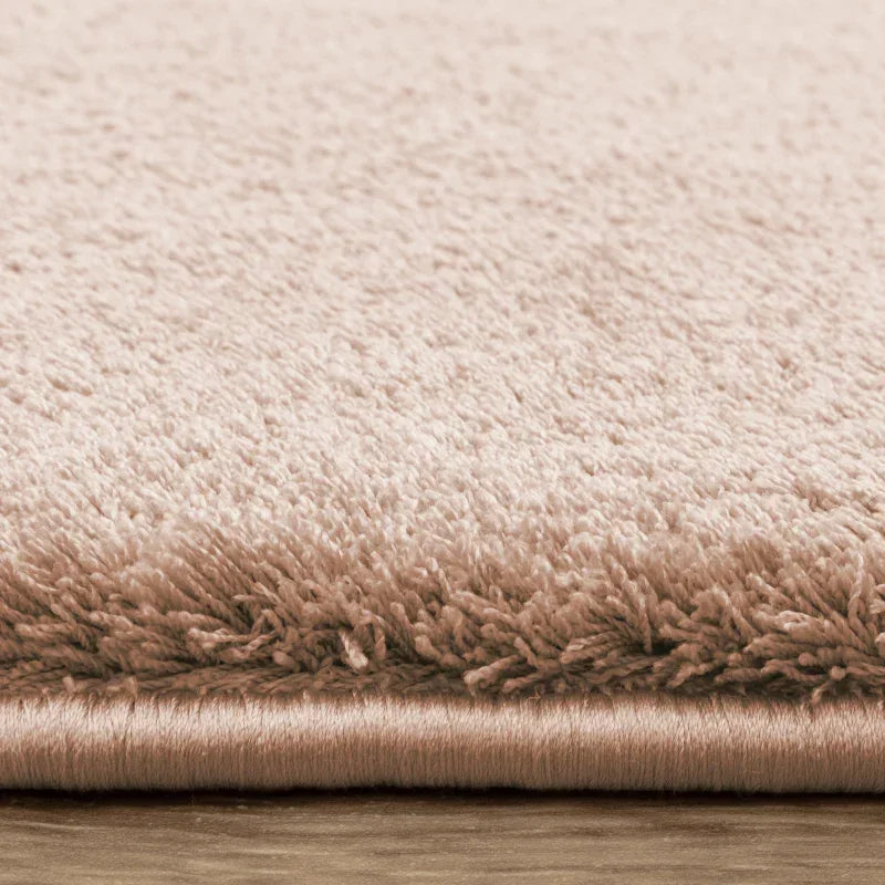 Close-up of beige shaggy rug edge on wooden floor