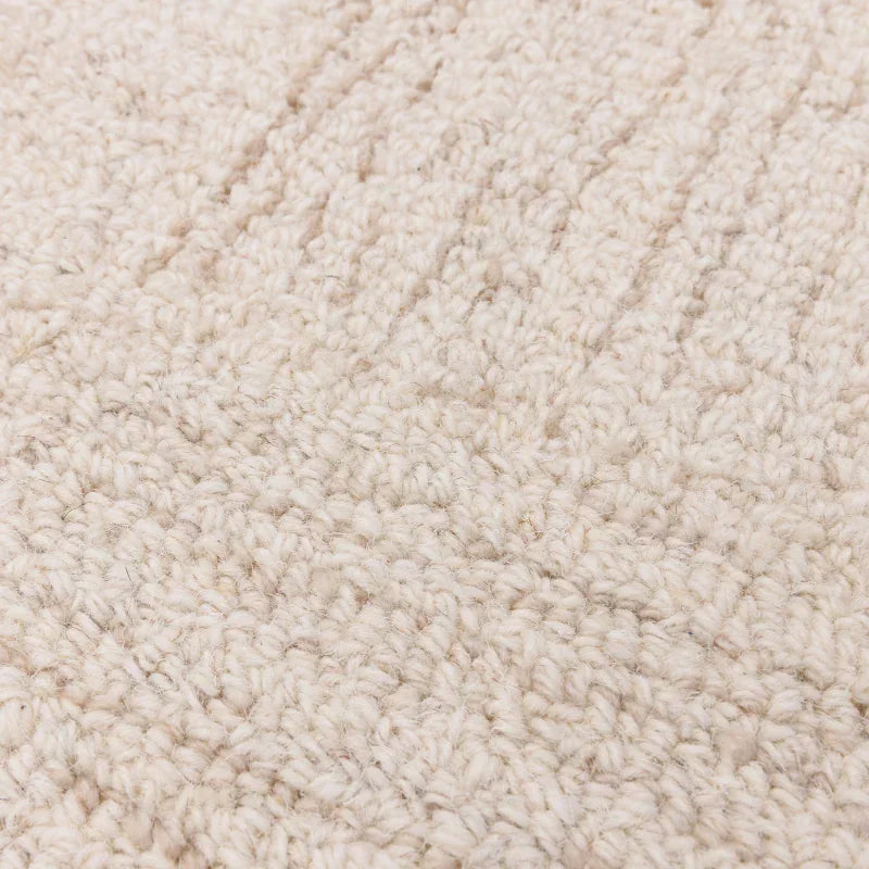 Textured cream wool rug close-up showing loop pile pattern and soft material