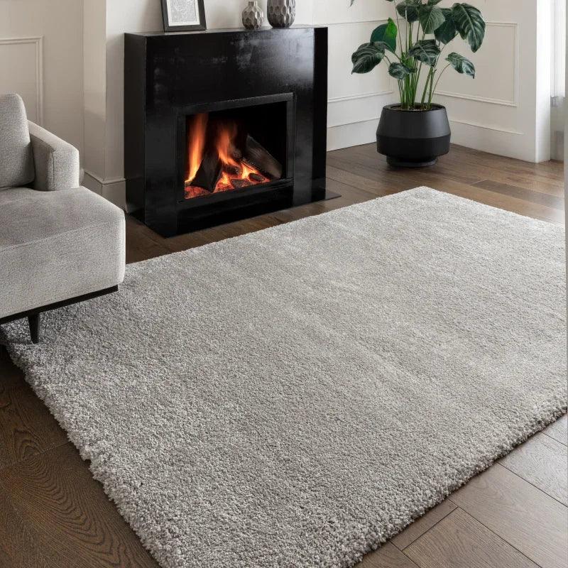 Light grey shaggy rug on wooden floor in modern living room with sofa and fireplace