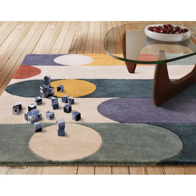 Modern geometric rug with colorful circles beside glass coffee table on wooden floor