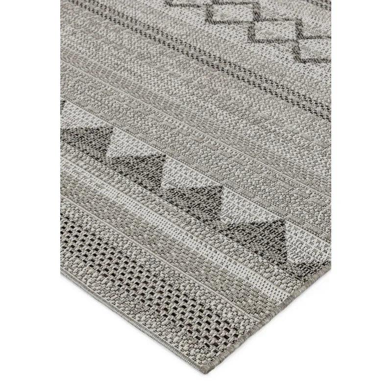 Grey patterned area rug with textured geometric design and woven details, corner view