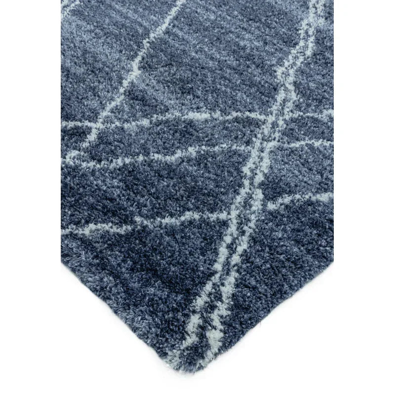 Blue shaggy rug with white geometric lines and soft textured pile, corner view
