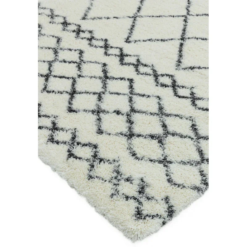 Cream shaggy rug with black geometric pattern, close corner view
