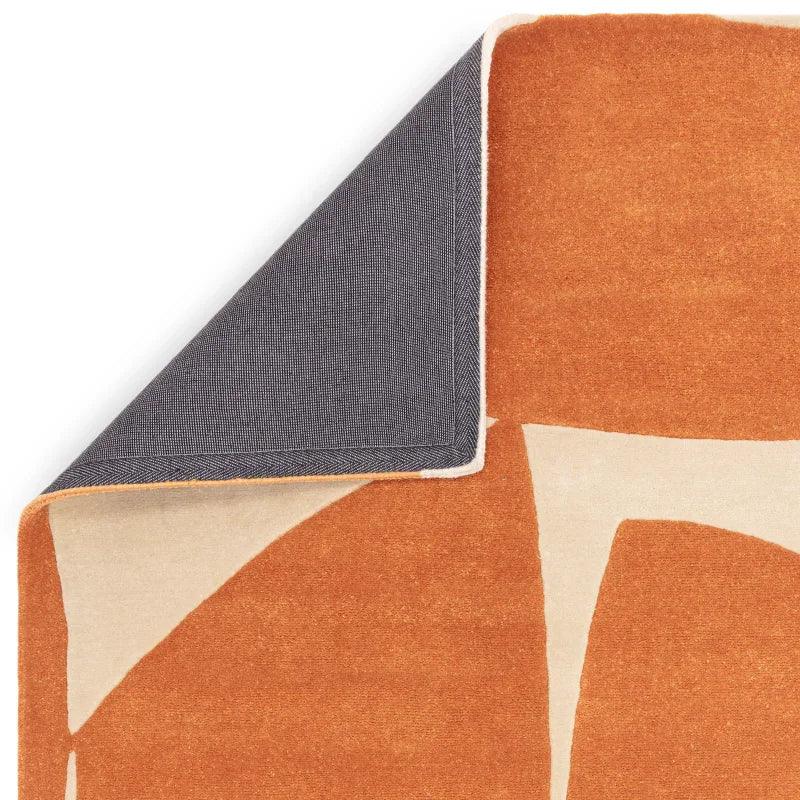 Orange and cream abstract area rug corner flipped to show backing
