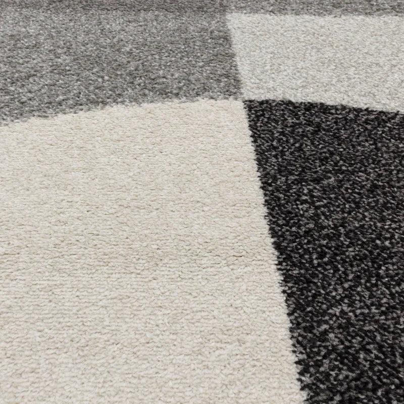 Close up of modern geometric rug with grey, black, and cream blocks