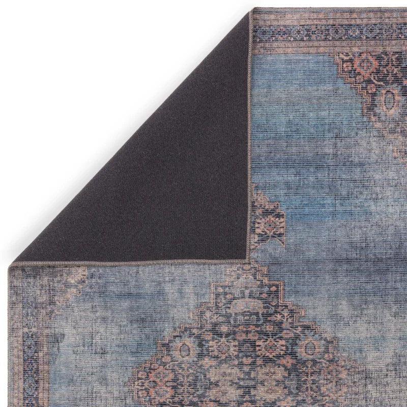 Distressed blue patterned area rug corner flipped to show non-slip backing