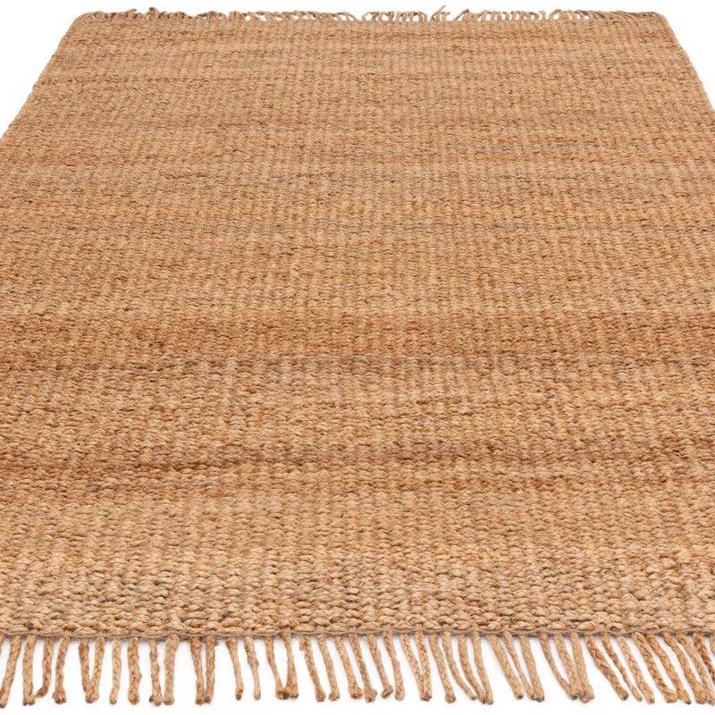 Large natural jute rug with woven texture and fringe edge, shown from angled view