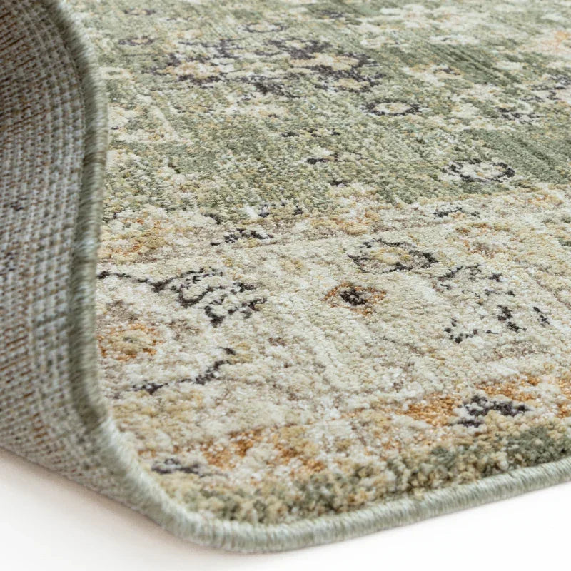 Close-up of patterned area rug with muted green and beige tones, showing textured weave