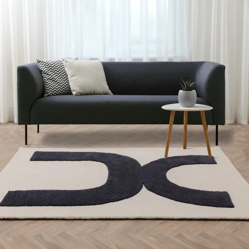 Modern black sofa with cushions, round side table, geometric patterned rug in living room