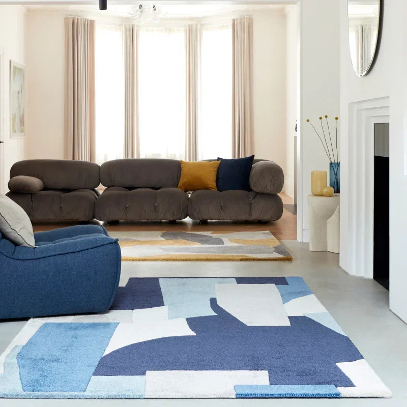 Modern living room with brown sofa, colorful abstract rug, and large bay window