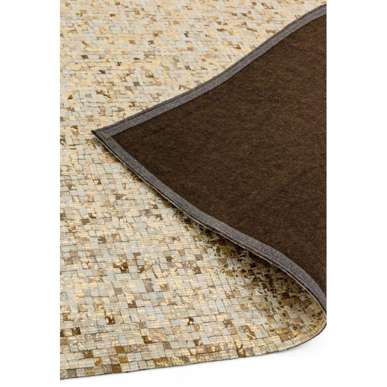 Beige and gold patterned area rug with brown felt backing, corner folded to show texture