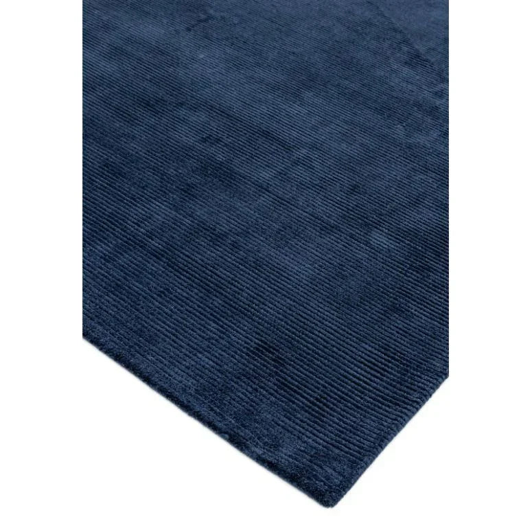Navy blue ribbed area rug corner with textured pattern and soft fabric finish