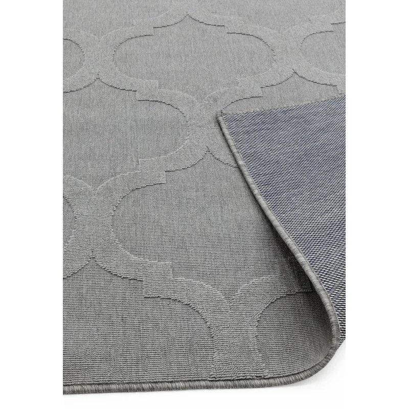 Grey area rug with geometric pattern and folded corner showing texture detail