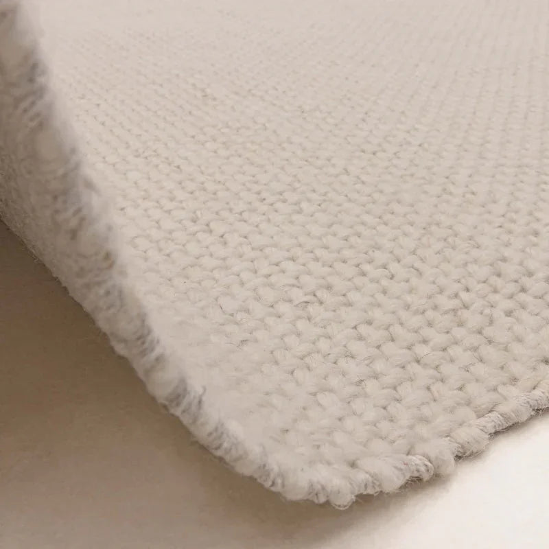 Closeup of cream woven wool rug showing texture and edge detail