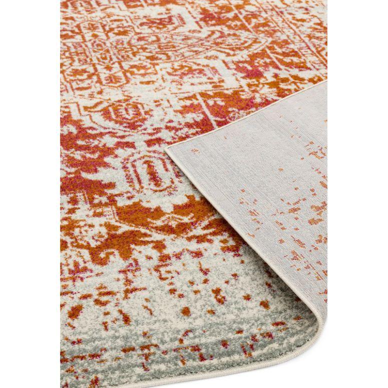Orange and cream patterned rug with corner flipped to show backing