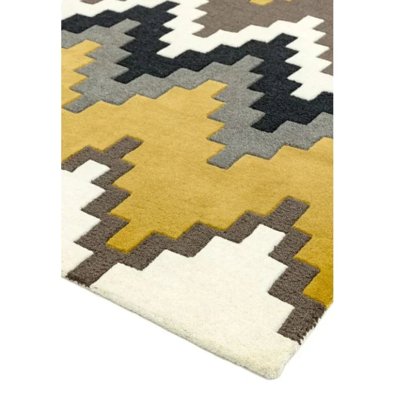 Modern geometric rug with mustard, white, grey, and black zigzag pattern, angled corner view