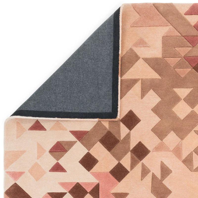 Geometric pattern area rug with pink and brown tones, corner turned to show backing