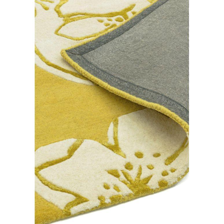 Yellow and cream floral area rug with corner folded to show backing detail