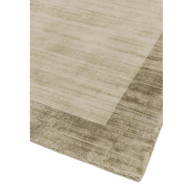 Beige area rug with subtle border design and textured finish, corner angle view