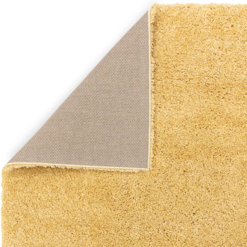 Beige shaggy rug with corner flipped to show textured non-slip backing