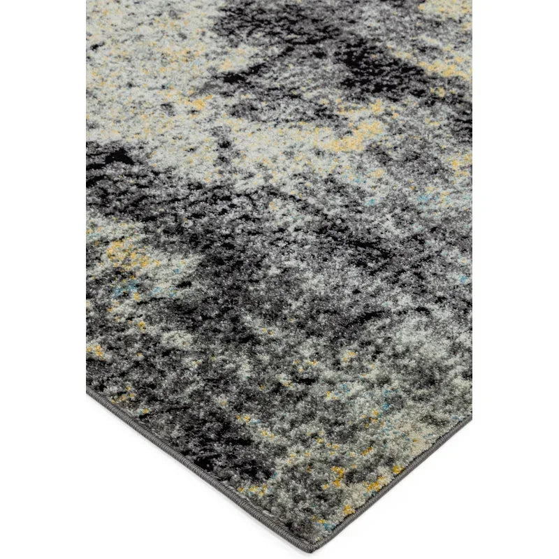 Grey abstract area rug with yellow and blue highlights, close-up of corner detail