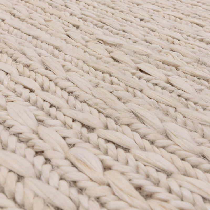 Close-up of cream woven wool rug texture with braided pattern detail